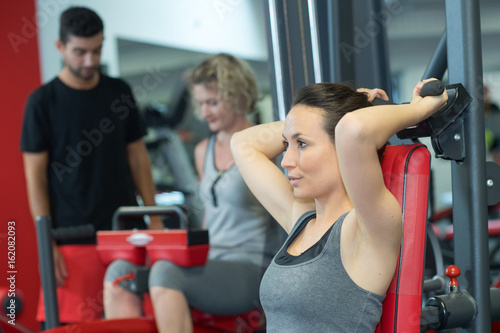 fit woman using weights machine for arms at the gym