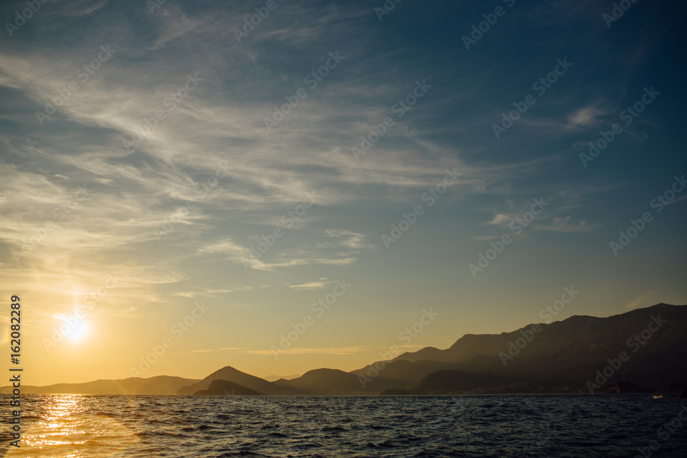 Coast of Montenegro at sunset, view from the sea, silhouettes of mountains