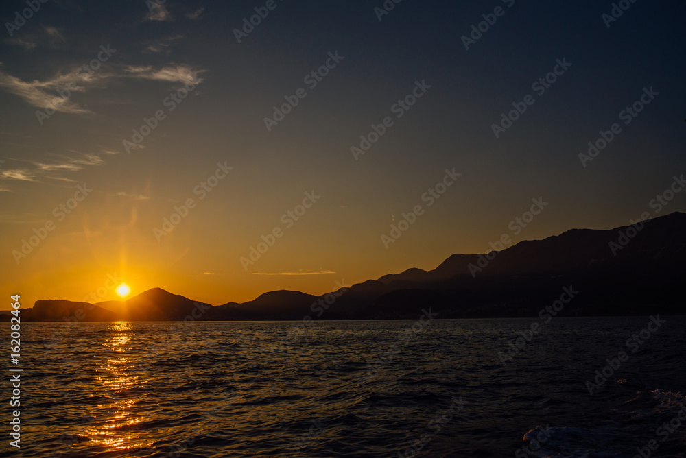 Coast of Montenegro at sunset, view from the sea, silhouettes of mountains