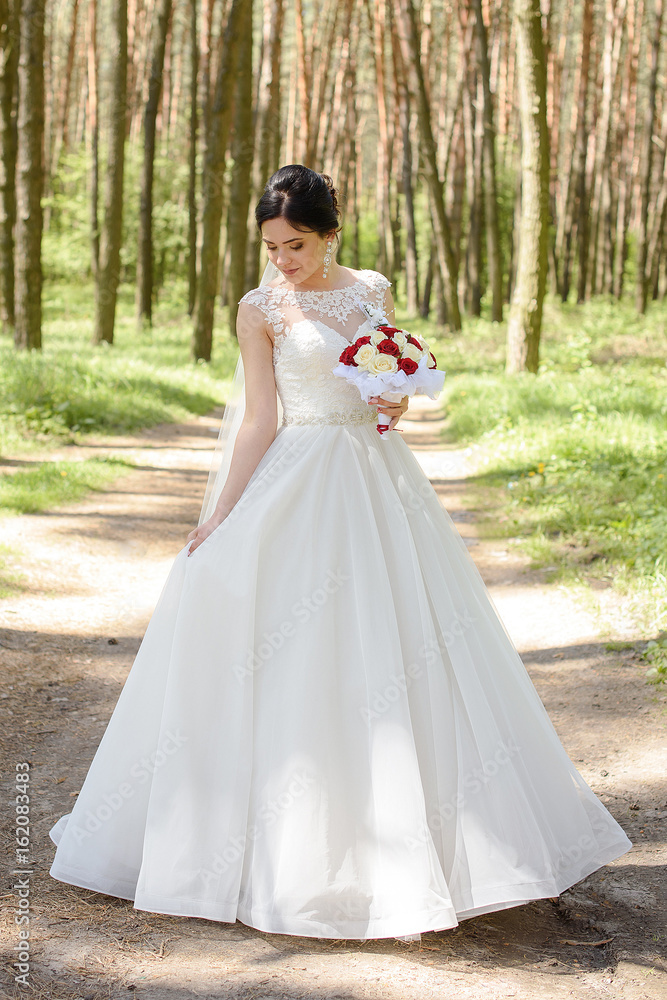 Beautiful bride perfect style. Wedding hairstyle make-up luxury wedding dress and bride's bouquet on wedding day. Beautiful bride outdoors in a forest. Beautiful bride perfect style. Wedding hairstyle make-up luxury wedding dress and bride's bouquet on wedding day. Beautiful bride outdoors in a forest.