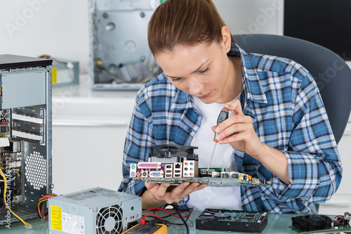 female electronician repairing computer motherboard