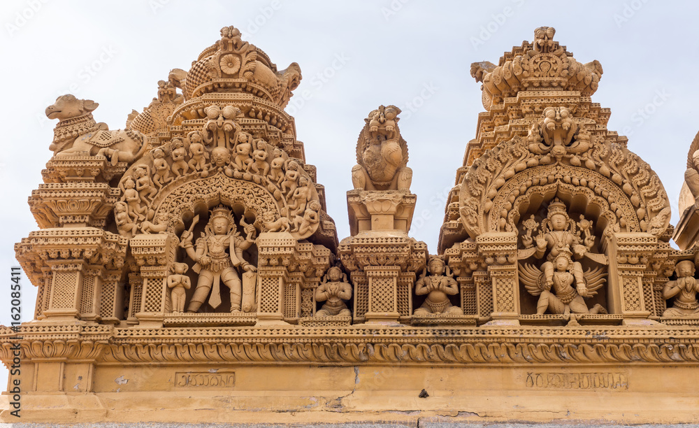 Nanjangud, India - October 26, 2013: Double Niche in beige elaborately decorated sandstone at Srikanteshwara Temple showing statue of Lord Shiva and of Lord Vishnu sitting on Garuda. 