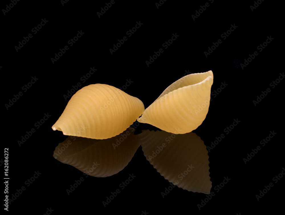 Fototapeta premium Macaroni on a black background, reflected in a glass