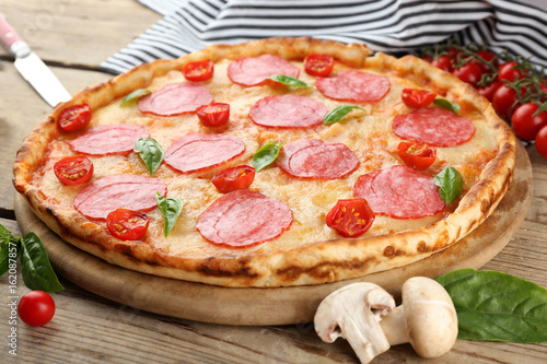 Pizza with salami on wooden background
