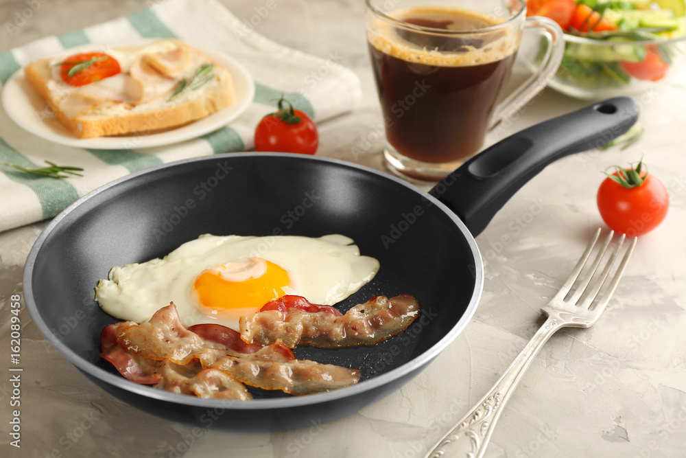 Frying pan with tasty egg and bacon for breakfast on table Frying pan with tasty egg and bacon for breakfast on table