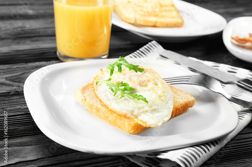 Plate with delicious over hard egg and bread slice on kitchen table © Africa Studio