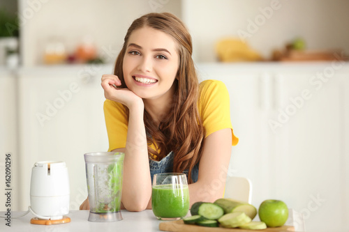 Weight loss concept. Beautiful young woman with fresh green smoothie in kitchen