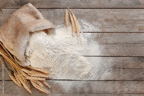 Bag with white flour on wooden background photo