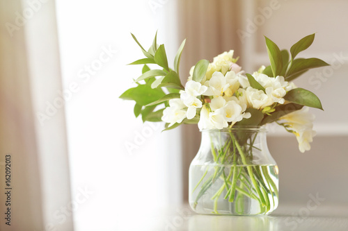 Beautiful bouquet with white freesia flowers on table at home