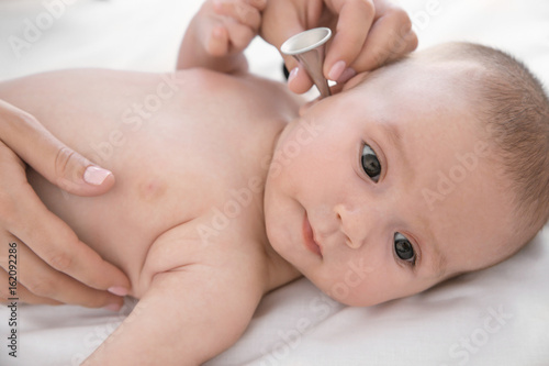 Doctor examining little baby with ear speculum in clinic, closeup. Baby health concept