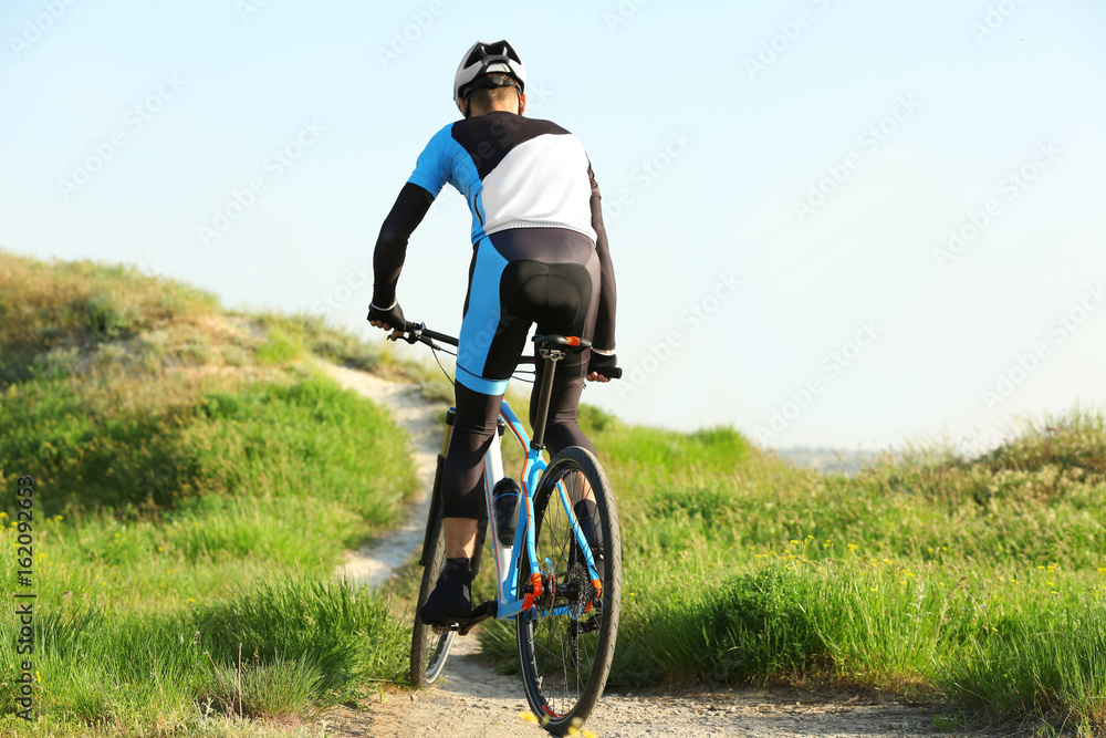 Sporty cyclist riding bicycle in countryside Sporty cyclist riding bicycle in countryside