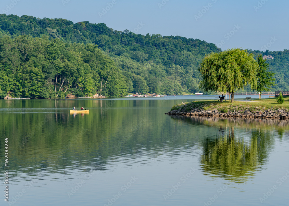 Couple paddling in yellow canoe on tree lined lake