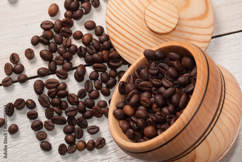 Coffee beans scattered from a Cup on white wooden background, wooden utensils, Coffee beans scattered from a Cup on white wooden background, wooden utensils,