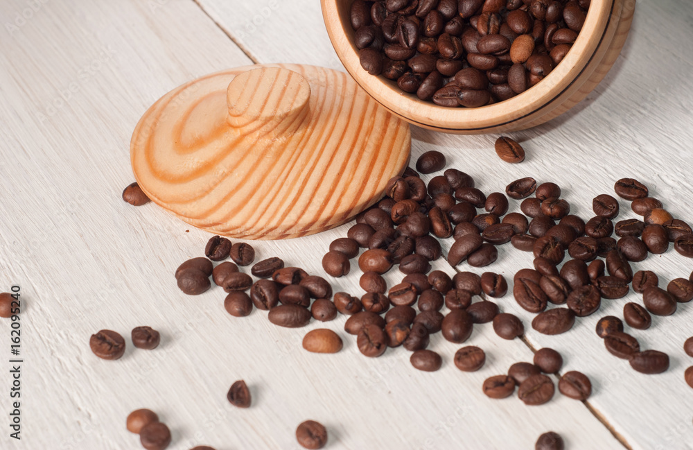 Coffee beans scattered from a Cup on white wooden background, wooden utensils, Coffee beans scattered from a Cup on white wooden background, wooden utensils,