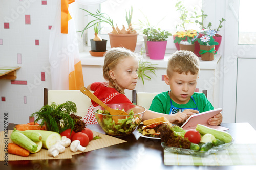 Obraz na płótnie Children prepare salad vegetables . Happy kids in the kitchen . The concept of a healthy wholesome food w salonie