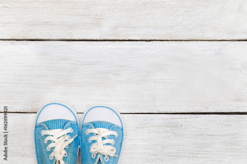 Children's blue shoes on a white wooden background. flat lay Children's blue shoes on a white wooden background. flat lay