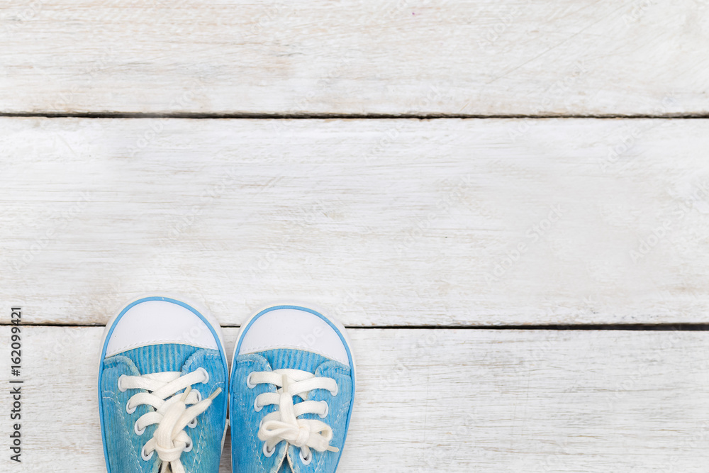 Children's blue shoes on a white wooden background. flat lay