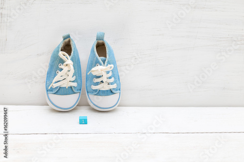 Children's sneakers in blue and a cube with a number one