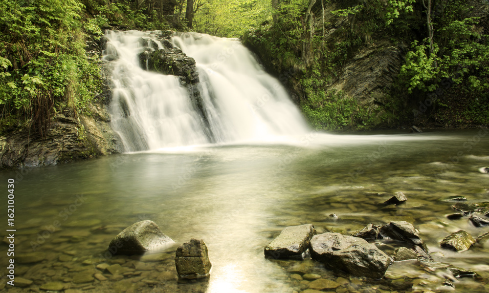 Fototapeta premium Wodospad i kamienie na pierwszym planie