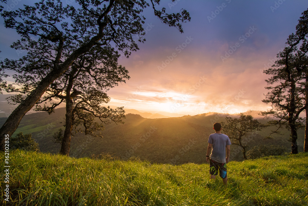 young man stand on mountain valley and enjoying sunset 