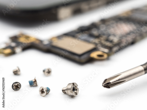 Wallpaper Mural Close-up image of screw and screwdriver with blurred smartphone components on white background Torontodigital.ca