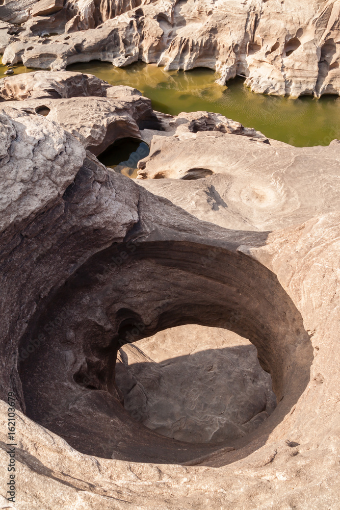 The stone hole caused by the water erode in Mekhong river after the water drops in summer,the Amazing of Rock in Mekhong River, Upon Ratcheting, Thailand.