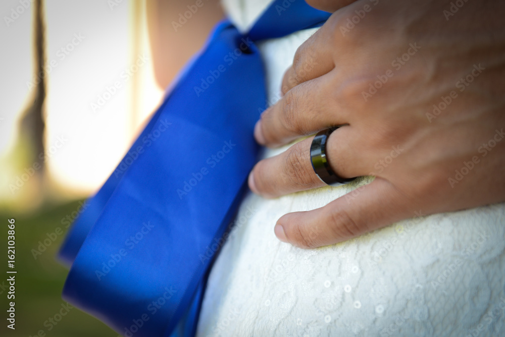 Hand with wedding ring, bride with a royal blue sash