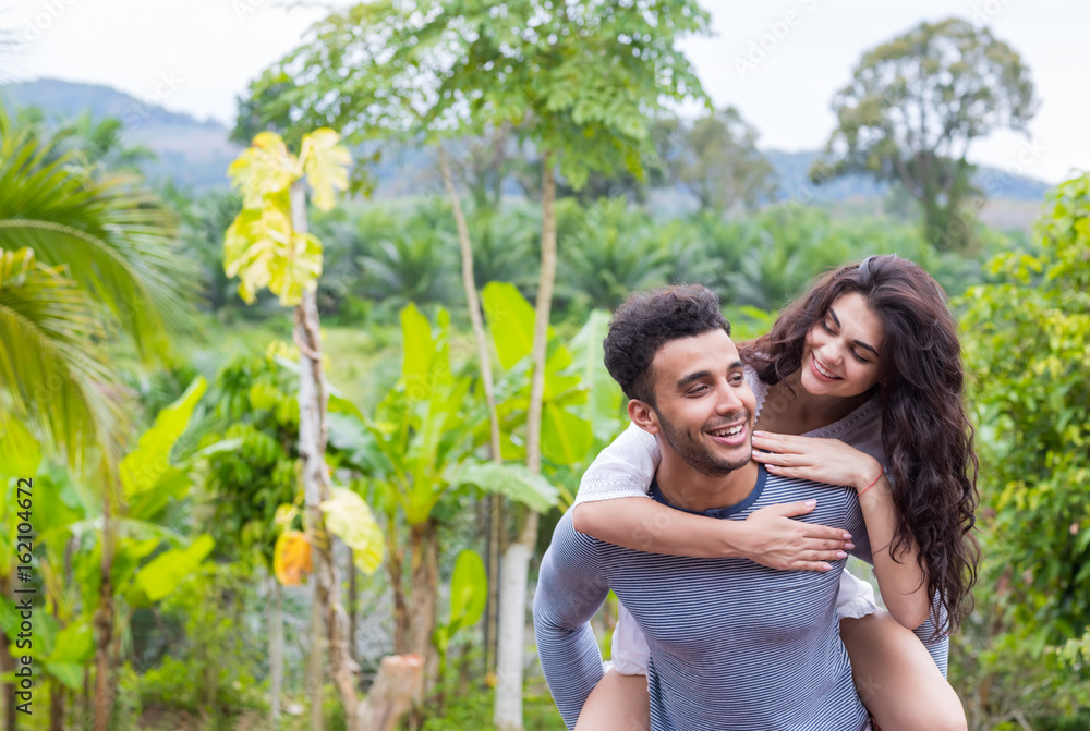 Happy Latin Man Carry Woman On Back, Young Couple Over Green Tropical Rain Forest Landscape Smiling Lovers Having Fun Happy Latin Man Carry Woman On Back, Young Couple Over Green Tropical Rain Forest Landscape Smiling Lovers Having Fun