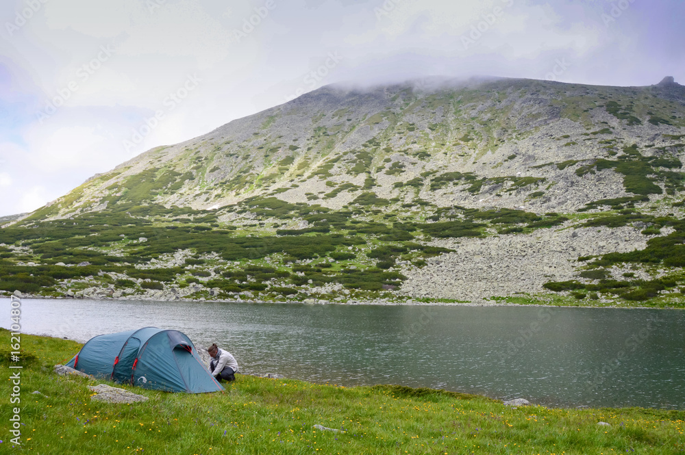 Man pitches a tent in mountains