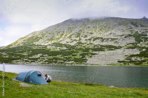 Obraz na płótnie Man pitches a tent in mountains w salonie