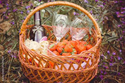 Basket for a picnic with strawberries  bread and wine. Summer sweets and joys  outdoor recreation