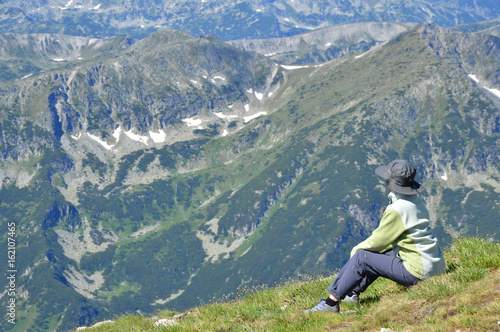 Obraz na płótnie Person hiker sitting on mountain peak w salonie
