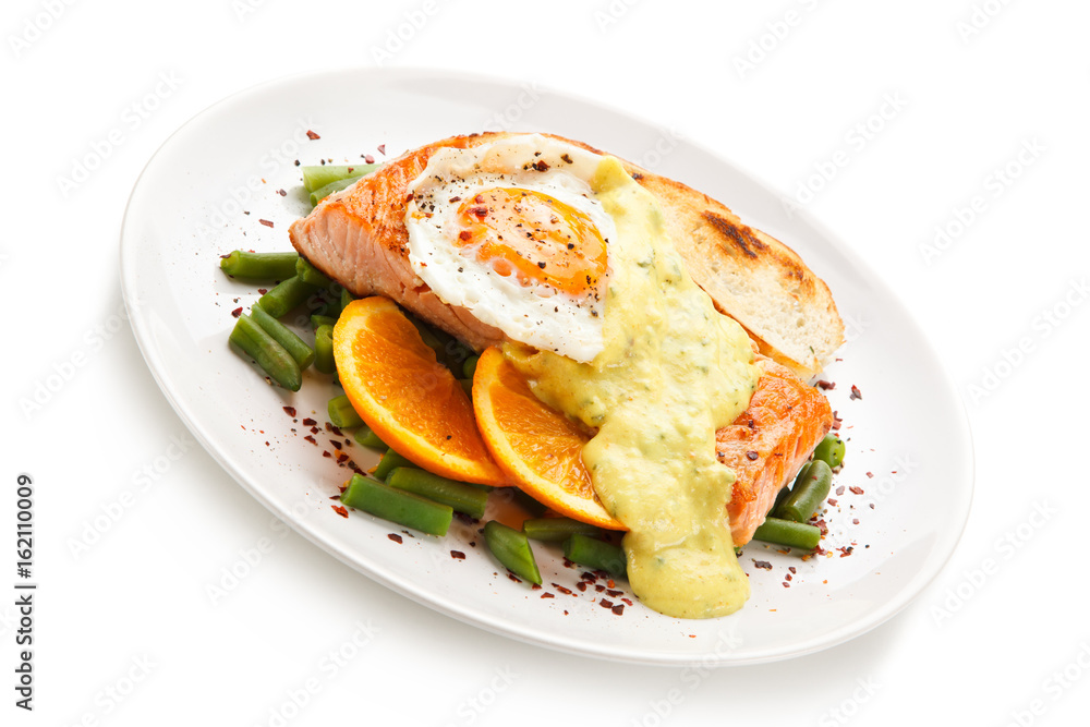 Grilled salmon with sauce, fried egg and vegetables on white background Grilled salmon with sauce, fried egg and vegetables on white background