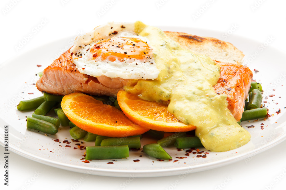 Grilled salmon with sauce, fried egg and vegetables on white background Grilled salmon with sauce, fried egg and vegetables on white background