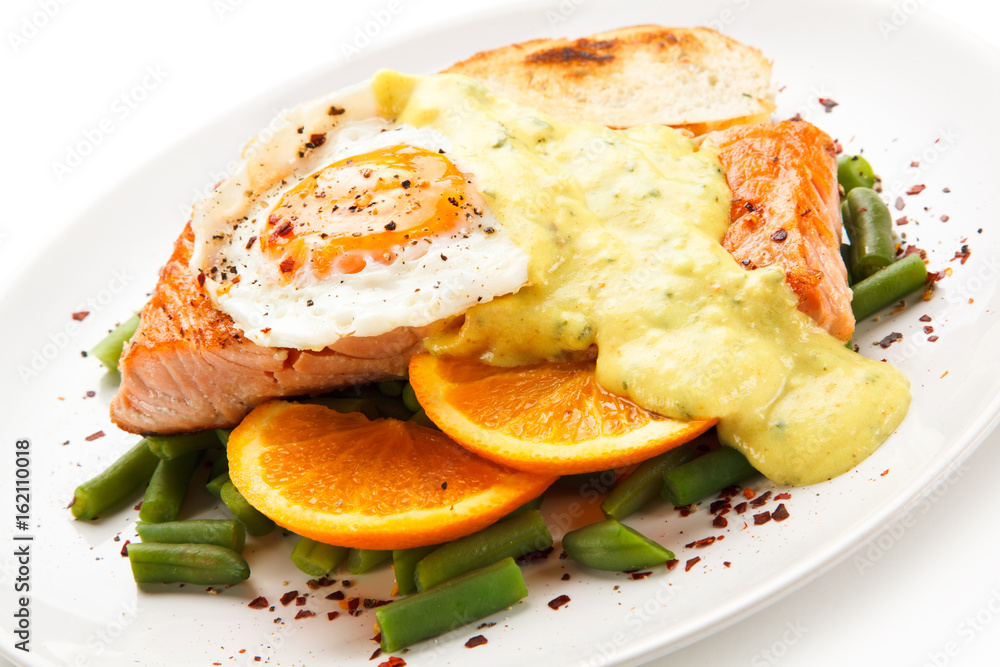 Grilled salmon with sauce, fried egg and vegetables on white background 