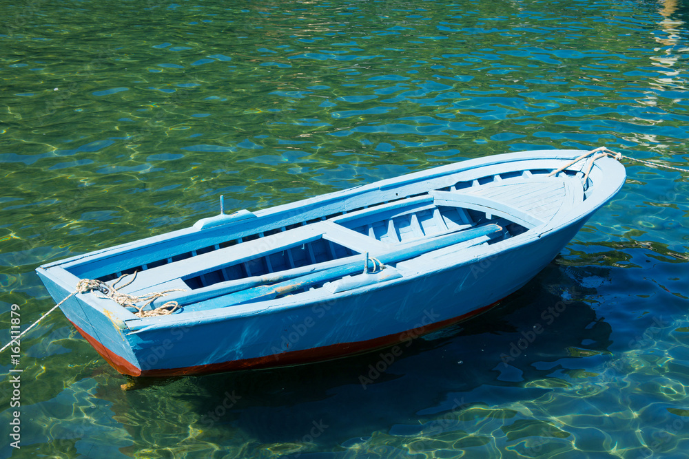 An old boat near a wooden bridge on a beautiful lake. Fishing boat on the pier.