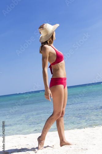 femme en maillot de bain marchant sur une belle plage 