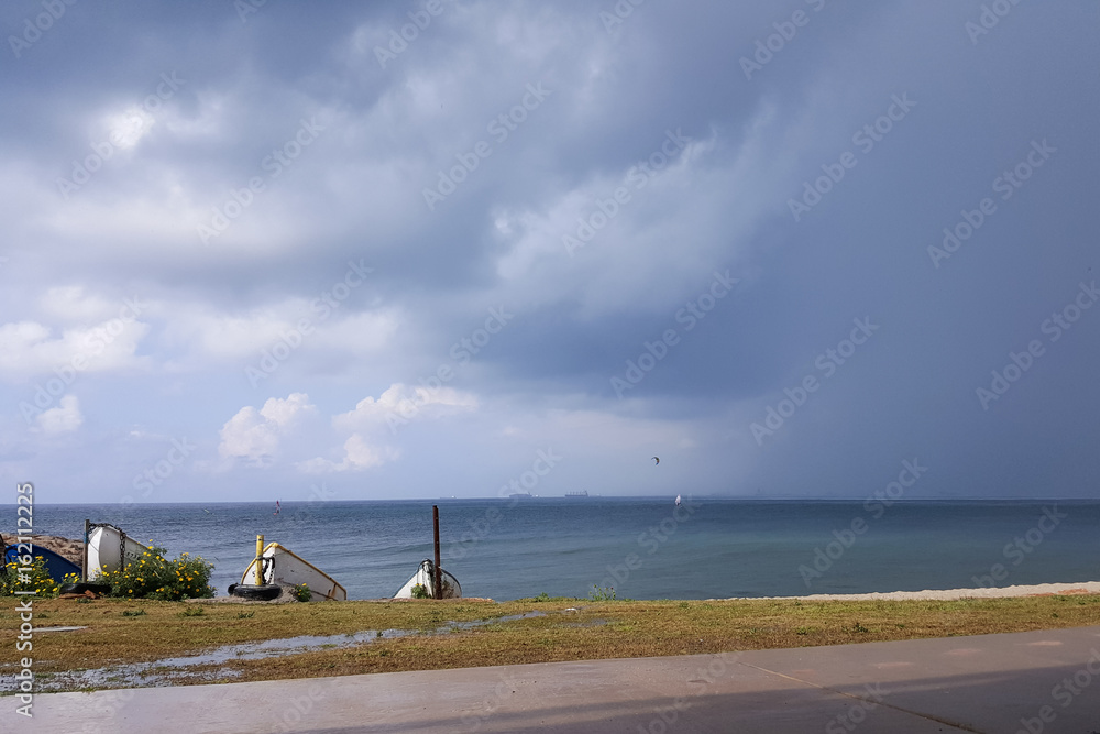 Cloudy weather on the seashore, surfers ride in the rain, hanging clouds