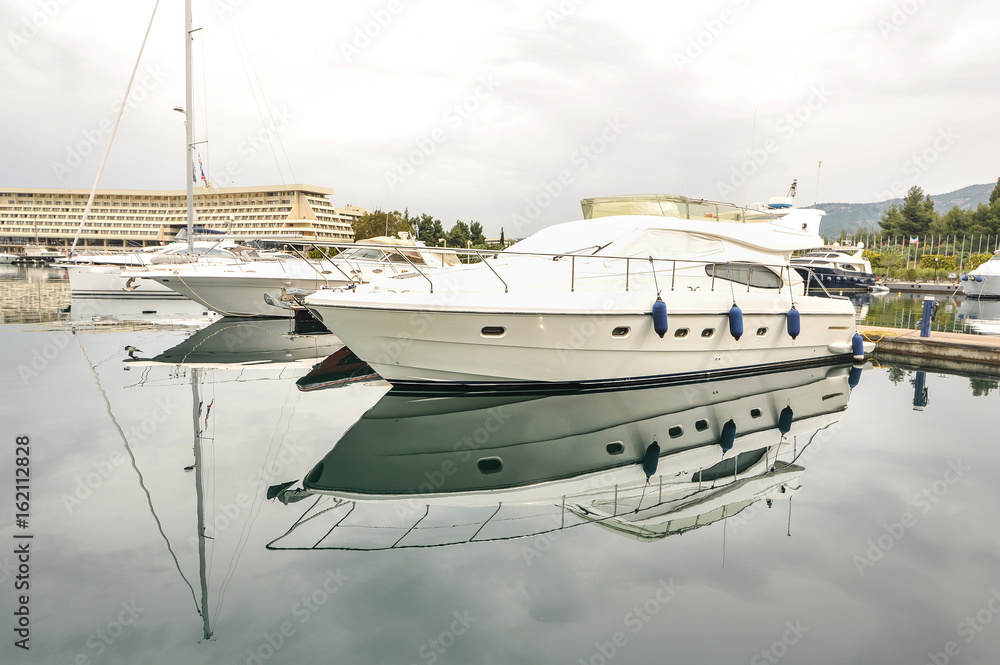 Fototapeta premium Yachts anchored at the marina.Sailboat harbor, many moored sail yachts in the sea port, modern water transport,summertime vacation, luxury lifestyle and wealth concept.Modern yachts in harbor