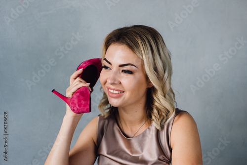 Beautiful girl holds a pink shoe in her hand