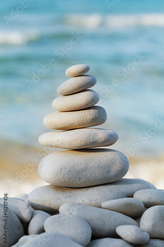 Stack of white pebbles stone against sea for spa, balance, meditation and zen theme.