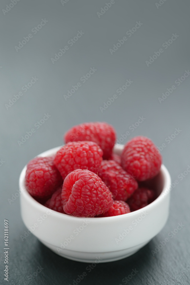 fresh raspberries in white bowl on slate board fresh raspberries in white bowl on slate board
