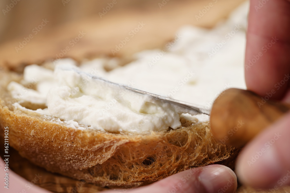 spreading ricotta cheese on fresh rustic bread spreading ricotta cheese on fresh rustic bread