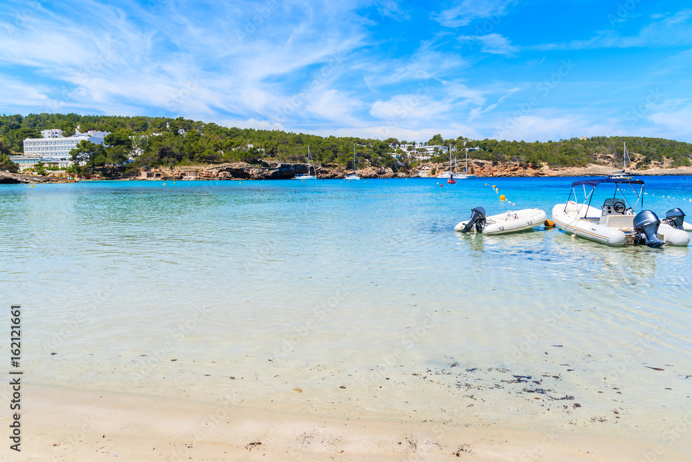 Dinghy motor boats in water on Cala Portinatx beach, Ibiza island, Spain