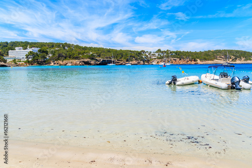 Dinghy motor boats in water on Cala Portinatx beach, Ibiza island, Spain