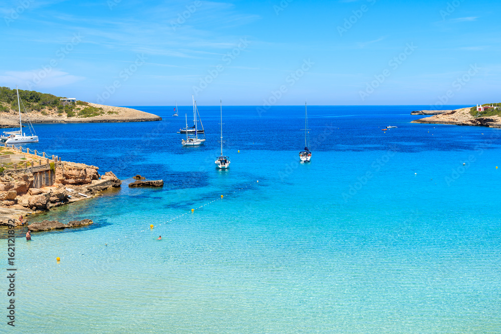 Sailing boats on blue sea in Cala Portinatx bay, Ibiza island, Spain