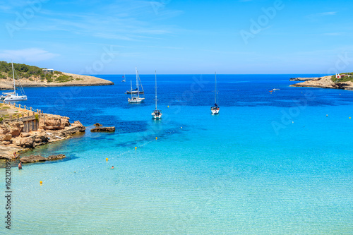 Sailing boats on blue sea in Cala Portinatx bay  Ibiza island  Spain