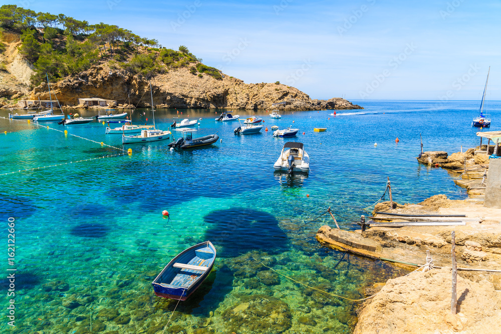 Obraz premium Fishing and sailing boats on blue sea water in Cala Vadella bay, Ibiza island, Spain