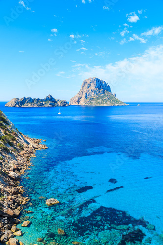 View of Cala d'Hort bay with beautiful azure blue sea water and Es Vedra island in distance, Ibiza island, Spain photo