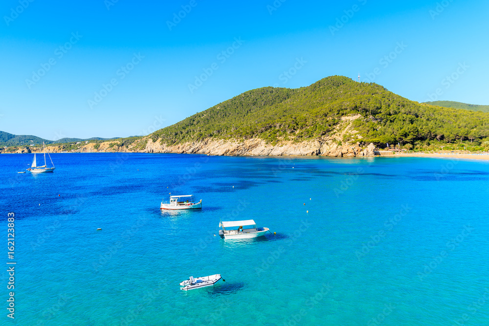 Fishing boats on blue sea water of Cala San Vicente bay, Ibiza island, Spain